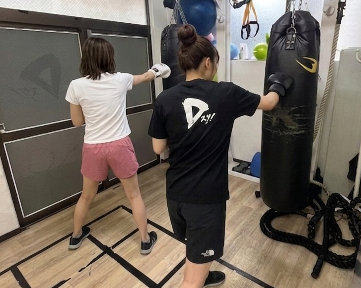 サンドバッグを打つ会員とトレーナー